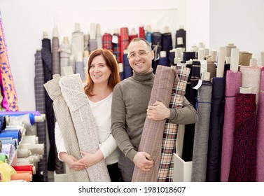 Family business team working together. Couple of two professional tailors holding rolls of fabrics cloth in atelier. Atelier or drapery store owners couple at working place. High quality photo - Powered by Shutterstock