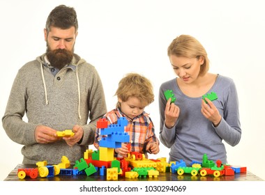 Family With Busy Faces Build Toy Cars Out Of Colored Construction Blocks. Mom, Dad And Kid In Playroom. Parenthood And Game Concept. Man With Beard, Woman And Little Boy Play On White Background.