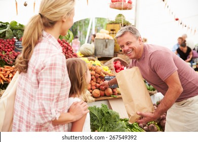 Family Buying Fresh Vegetables At Farmers Market Stall