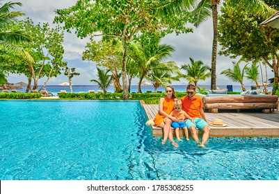 Family By Poolside, Young Couple With Three Year Old Toddler Boy. Resort Swimming Pool At Mahe, Seychelles.