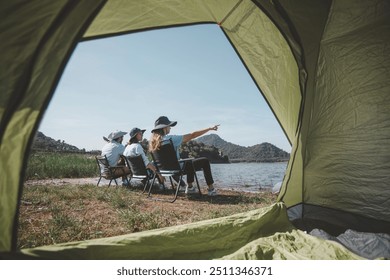 Family camping by a lake, raising their bottles in a toast appears to be a camping trip a guitar, suggesting a day filled with music enjoyment in nature holiday trip.  - Powered by Shutterstock