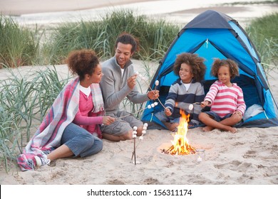 Family Camping On Beach And Toasting Marshmallows