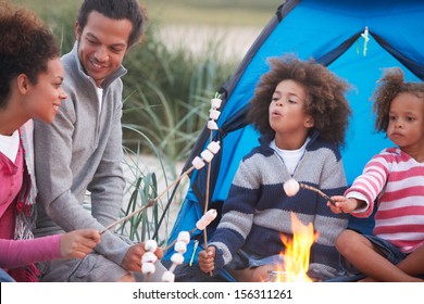 Family Camping On Beach And Toasting Marshmallows