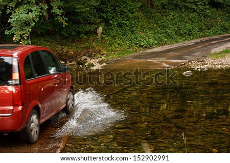 Family Car fording a river at ford an old fashioned way of crossing water without building a bridge