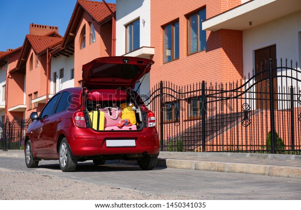Family car with open trunk full of luggage in city.
Space for text