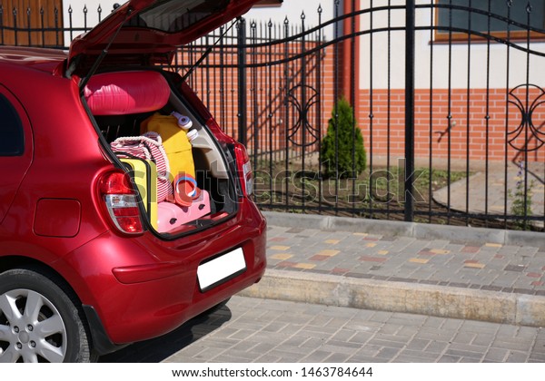 Family car with open trunk full of luggage in city.\
Space for text