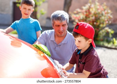 Family Car Wash, Men At Work. Little Boy In Cap Cleaning The Headlight