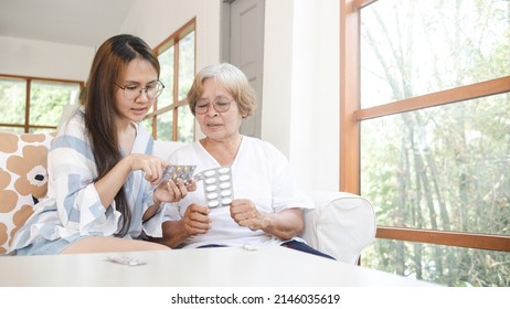 Family Care Concept And The Elderly, An Asian Woman Reading A Label Recommending Her Mother In Taking Medicine.