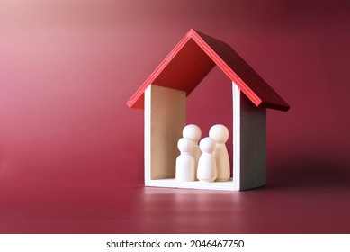 Family care, protection and insurance concept. Wooden dolls family inside a house. - Shutterstock ID 2046467750