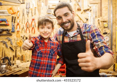 family, carpentry, woodwork, gesture and people concept - happy father and little son making thumbs up at workshop - Powered by Shutterstock