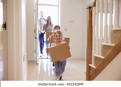 Family Carrying Boxes Into New Home On Moving Day