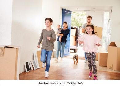 Family Carrying Boxes Into New Home On Moving Day