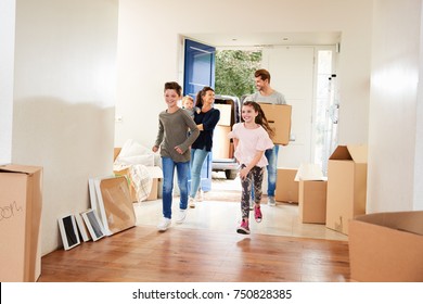 Family Carrying Boxes Into New Home On Moving Day