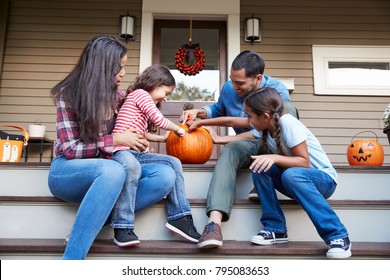 Family Carving Halloween Pumpkin On House Steps