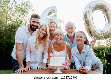 Family Celebrating A  60th Birthday, With Balloons And Cake, Happy, Cheering 