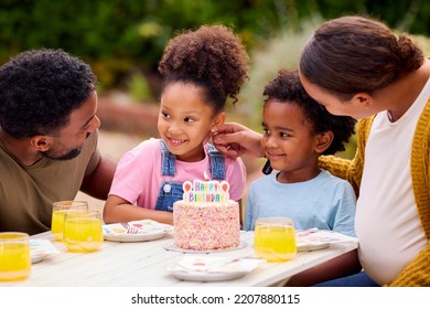 Family Celebrating Child's Birthday In Garden At Home Blowing Out Candles On Cake - Powered by Shutterstock