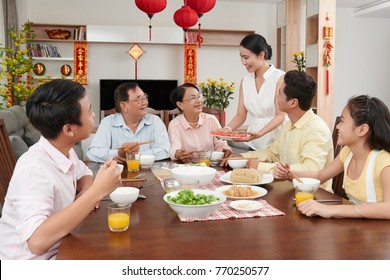 Family celebrating Chinese spring festival at home; couplets with best wishes for the upcoming year in the background