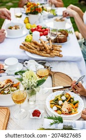 Family Celebrations And Food Concept. The Family Is Having Dinner At A Summer Garden Party. Table Setting And Decoration. Food And Drinks. BBQ, Vegetables, Wine And Other Snacks. Life In The Suburbs