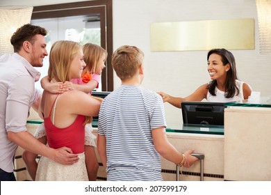 Family Checking In At Hotel Reception