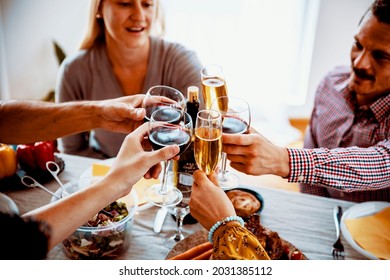 Family Cheering With Drink At Festive Dinner. Drinking Wine Over Thanksgiving Holiday Food. Friends Celebrate And Toasting On Special Event