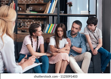 Family Cheering Up Woman On Therapy Session By Female Counselor In Office 