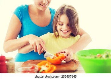 Family, Child, Cooking And Home Concept - Smiling Little Girl With Mother Chopping Pepper In The Kitchen