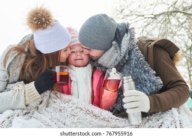 Family With Child Drinking Tea And Cuddling In Winter