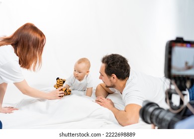 family with a child. Happy family is sitting on the floor. Father, mother and child have fun together. minimalist interior. baby photoshoot in studio