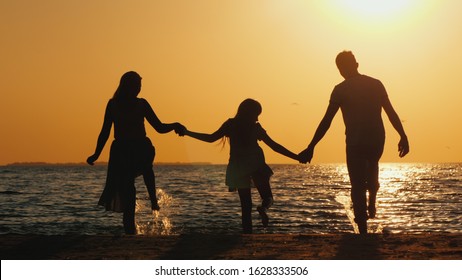 Family with a child to have fun on the beach in the rays of the setting sun