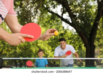 Family with child playing ping pong in park, closeup