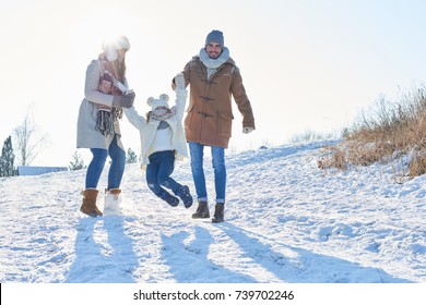 Family With Child Playing In The Snow Together In Winter