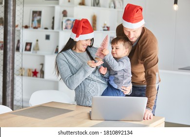 Family With A Child In Their Arms In The Living Room Video Chat At Christmas