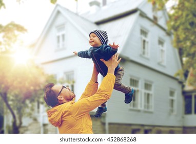 Family, Childhood, Fatherhood, Leisure And People Concept - Happy Father And Little Son Playing And Having Fun Outdoors Over Living House Background