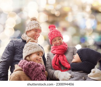 Family, Childhood, Season, Holidays And People Concept - Happy Family In Winter Clothes Over Lights Background