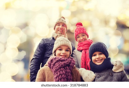 Family, Childhood, Season, Holidays And People Concept - Happy Family In Winter Clothes Over Lights Background