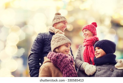 Family, Childhood, Season, Holidays And People Concept - Happy Family In Winter Clothes Over Lights Background