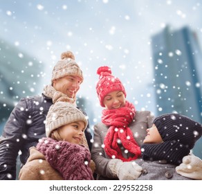 Family, Childhood, Season And People Concept - Happy Family In Winter Clothes Over Snowy City Background