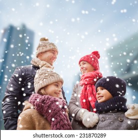 Family, Childhood, Season And People Concept - Happy Family In Winter Clothes Over Snowy City Background