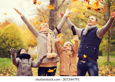 Family, Childhood, Season And People Concept - Happy Family Playing With Autumn Leaves In Park