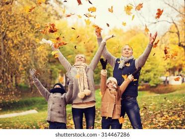 Family, Childhood, Season And People Concept - Happy Family Playing With Autumn Leaves In Park