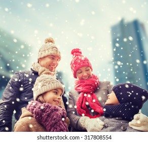 Family, Childhood, Season And People Concept - Happy Family In Winter Clothes Over Snowy City Background