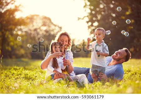 Family with children blow soap bubbles outdoor