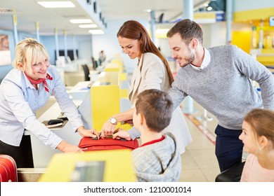 Family With Children At The Check-in Desk In The Airport Drop Off Their Luggage