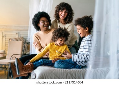 Familienkinder, homosexuelle Eltern Konzept. Happy multi-ethnische Frauen, die sich zu Hause mit Kindern amüsieren