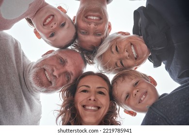 Family, Children And Grandparents With A Girl, Boy And Parents Standing In A Huddle Or Circle Outdoor From Below. Kids, Love And Bonding With A Man, Woman And Grandkids Spending Time Together Closeup