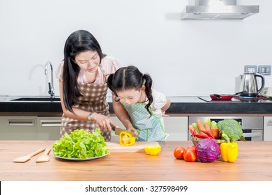 Family, Children And Happy People Concept - Asian Mother And Kid Daughter Cooking In The Kitchen At Home. Looking Happy Family