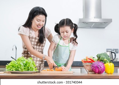 Family, Children And Happy People Concept - Asian Mother And Kid Daughter Cooking In The Kitchen At Home
