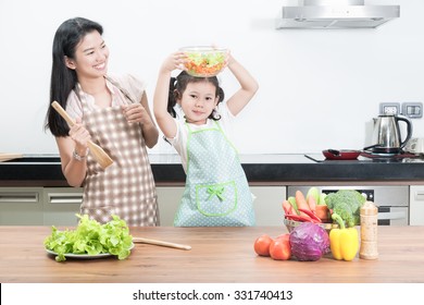 Family, Children And Happy People Concept - Asian Mother And Kid Daughter Cooking In The Kitchen At Home