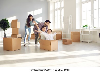 Family with children having fun in new home. Joyful first-time buyers with kids playing with boxes in living room. Real estate, residential mortgage, moving into dream house, happy future concept