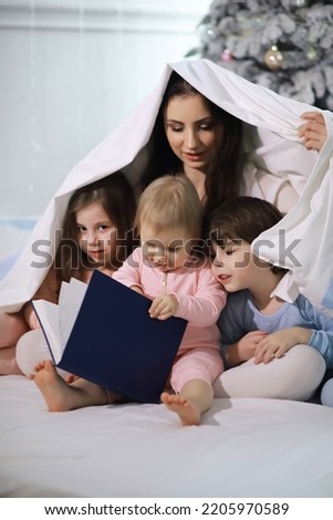 Similar – Mother reading book to her sons in the bed